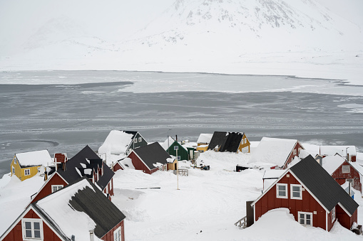 Community on a frozen bay and snowcapped mountains
