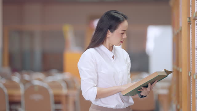 A woman is reading a book in a library