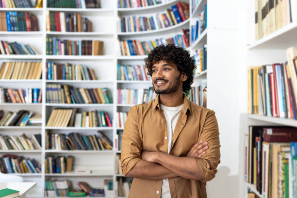 istock Confident young man with curly hair standing in a library 2105373915