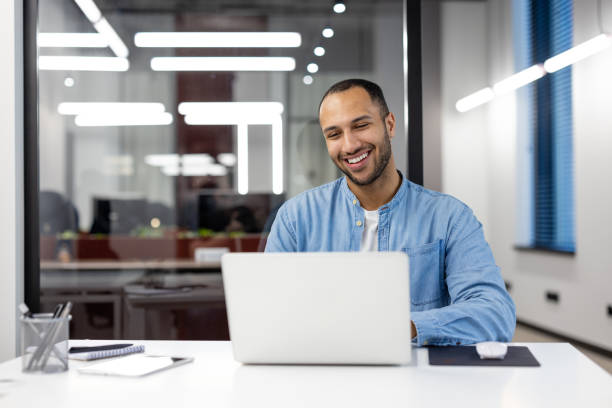 Smiling businessman using laptop in modern office