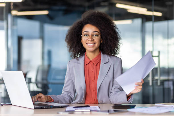 istock Confident young businesswoman with documents at her office desk 2105416622