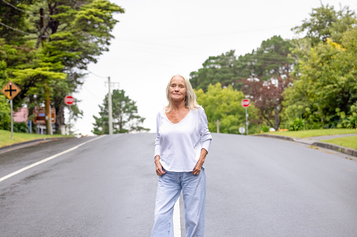 Senior woman walking in sunny day on the road, background with copy space, full frame horizontal composition