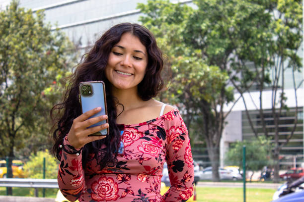 istock Young beautiful woman using cell phone in front of modern building 2105477126