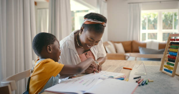 istock Black family, education and mother laughing with child in home for development, learning or study. Book, homework and writing with woman helping kid school student in dining room of apartment 2105489313