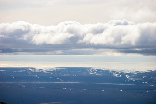 Heavy clouds sit above the ocean and lava flats on the edge of Iceland's south coast