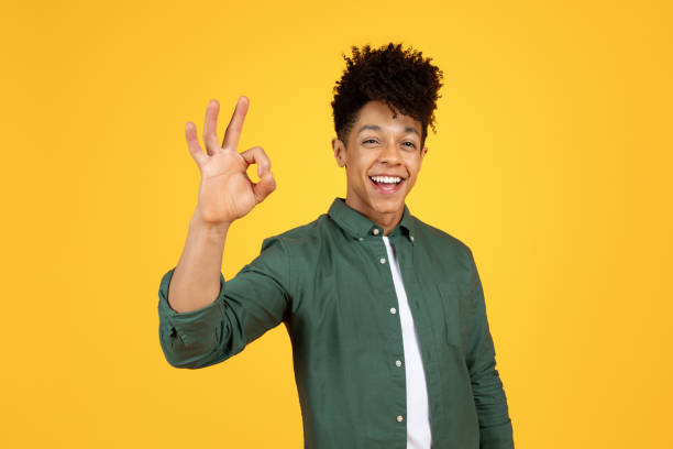 istock Positive black guy showing okay gesture, yellow background 2105491451