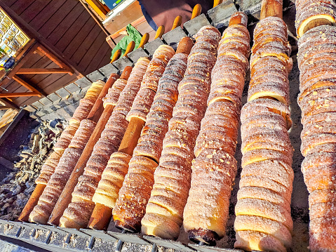 Process of baking trdelnik in Prague, Grilled rolled dough topped with Cinnamon sugar, The food is about vegag, lean. Traditional Czech hot sweet pastry, street bakery in Prague. High quality photo