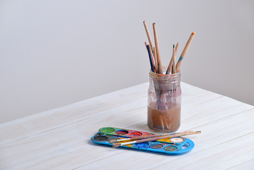 Jar with brushes and watercolors on wooden table. Great for creative projects or artistic themes