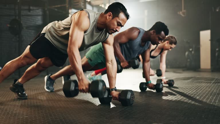 Gym, group and dumbbell rowing exercise for power, muscle and challenge in workout class. Diversity of strong people, bodybuilding and push up with weights for fitness, healthy training and action