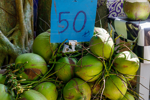 A heap of coconuts for sale on a Thailand street, priced at 50 baht each