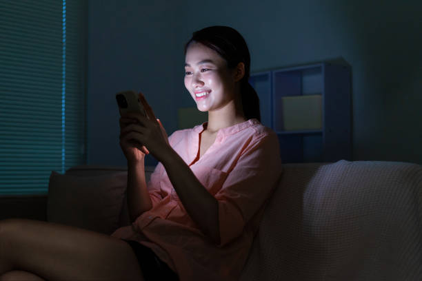 istock Young Asian woman using phone in the dark at night 2105647085