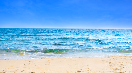 Beach sand background for summer vacation concept. Beach nature and summer seawater with sunlight light sandy beach Sparkling sea water contrast with the blue sky.