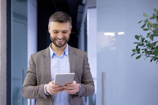 istock Mature experienced businessman inside office smiling contentedly, senior man holding tablet computer in hands, boss in business suit using analytical financial application 2105735501