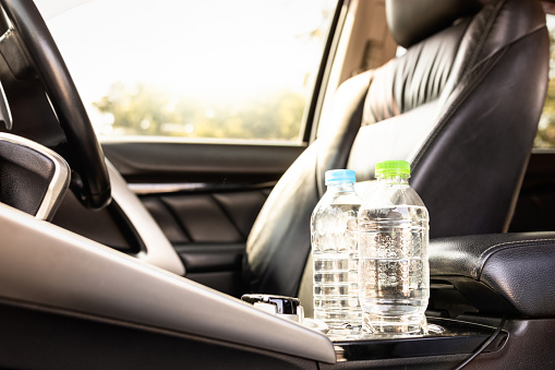 Plastic bottle of water placed on car seat and exposed to sun in sunny day,bottle of drinking water in car,sunlight,very hot,heating temperature,cause danger if parked in the sunshine for a long time