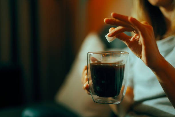 istock Hand Adding One Cube of Sugar in her Black Coffee 2105771540