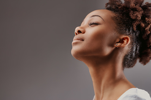 Her profile stands against a soft background, her expression a silent testament to thoughtful serenity