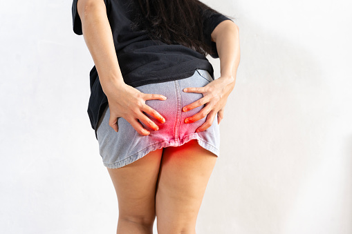 Mujer que sufre de hemorroides. La mujer sostiene su trasero debido al dolor abdominal y las hemorroides, concepto de cuidado de la salud. photo