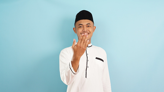 Young muslim man inviting gesture with smile isolated on blue light background
