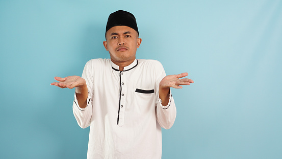 Muslim man not knowing , confused, clueless gesture on blue background