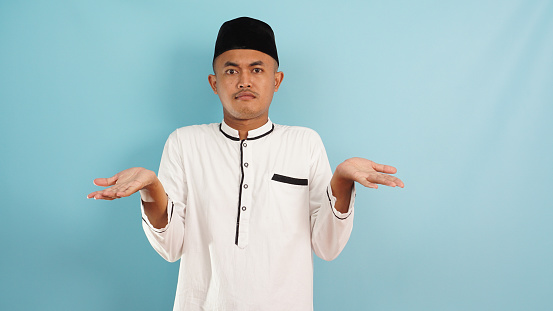 Muslim man not knowing , confused, clueless gesture on blue background
