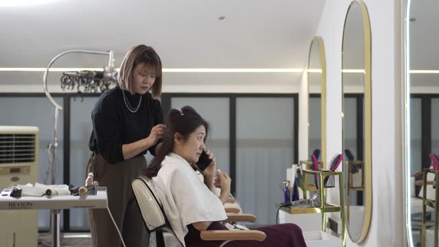 Asian Chinese hairstylist curling customer hair