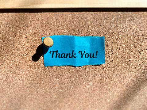 Thank you on blue torn paper on board background. Gratitude concept.