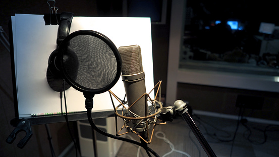 Microphone with pop filter and shock mount anti-vibration and note stand and tripod in music score studio production