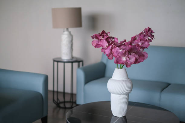 Close-up shot of white ceramic vase with beautiful pink flower arrangements on the living room