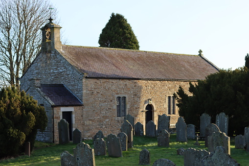 Small country church in morning sunshine surrounded by headstones