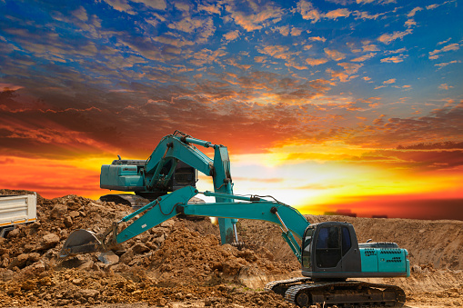 Crawler excavator digging the soil,In the construction site on the sunset sky background .