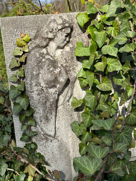Vienna, Austria - December 20, 2024: Weathered stone statue of a seated robed figure in a cemetery, with its head broken off, symbolizing decay and the passage of time.