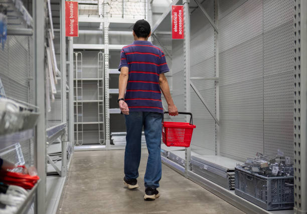 Man carrying a shopping basket, walking among the empty shelves. Stores closing down during the economic depression. Man carrying a shopping basket, walking among the empty shelves. Stores closing down during the economic depression. insufficient funds stock pictures, royalty-free photos & images