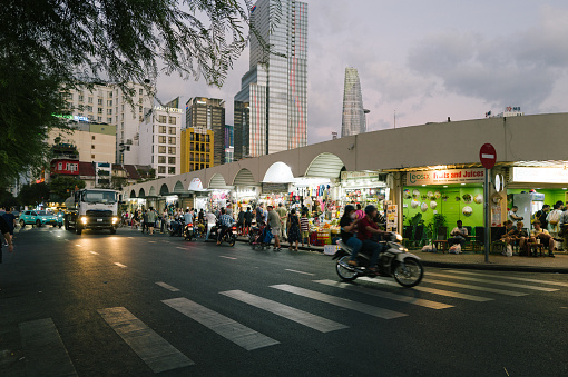 Bui Vien Street perspective, numerous signboards, people, motorbikes, Bitexco Tower. The colorful area is famous Saigon tourist attraction located in District 1, Ho Chi Minh City, Vietnam.