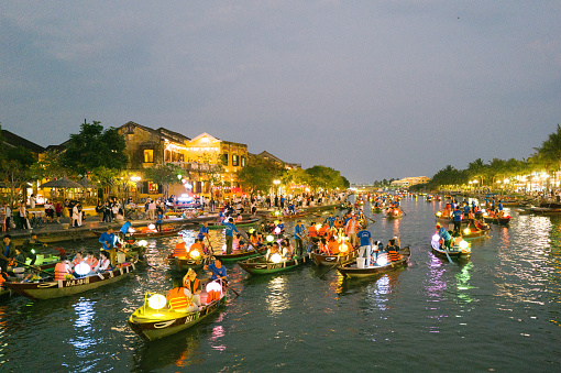 Hoi An, Vietnam - 20 February 2024: Boats decorated with colorful paper lanterns sail with tourists on the Bho Tan River along the historic old quarter.