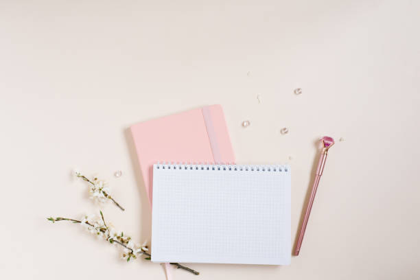 istock A blank notebook sheet with a sprig of white apple blossoms, a pink notebook and a pink pen on a beige background. Spring concept for a blog 2106093906