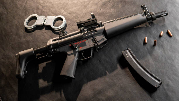 istock A machine gun and a set of handcuffs rest upon the table. 2106095425