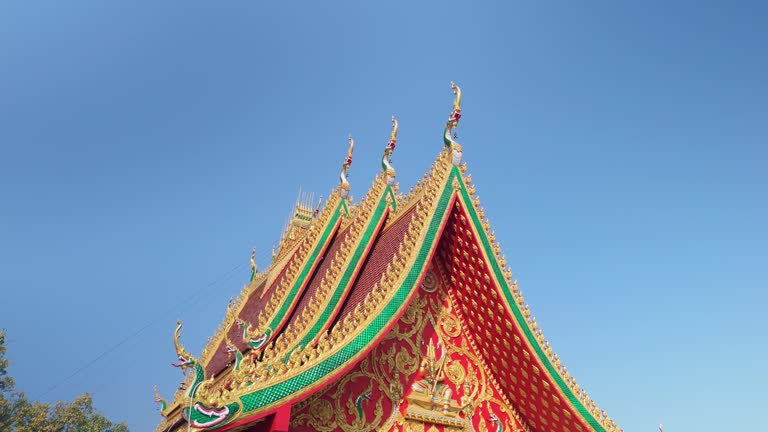 Exotic styled curved pagoda roof. Laotian architecture. Drone aerial rotate, blue sky.