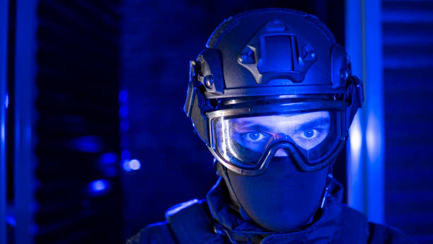 A portrait of a special forces agent wearing assault gear looks seriously at the camera through the glass of a mask