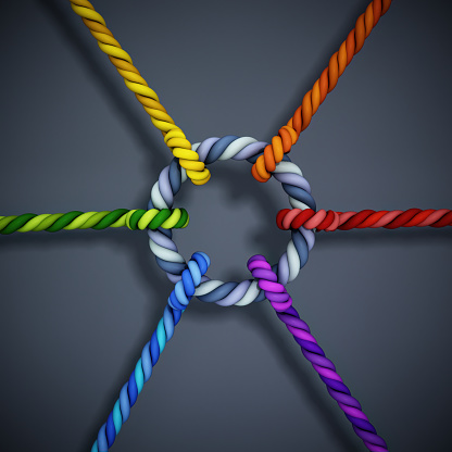 Vibrant Multi-Colored Ropes Tied Together in Intricate Knots Against a Gray Background. Teamwork and collaboration concept.