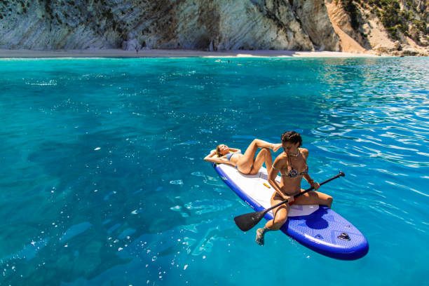 istock Two attractive young woman on a paddleboard in sea 2106142139