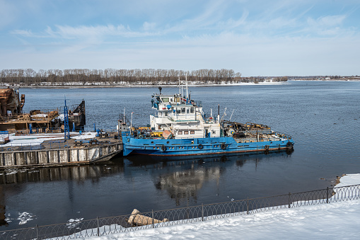 River transport, equipment, tugs, dredger, crane at the pier during the onset of spring. Industrial landscape.