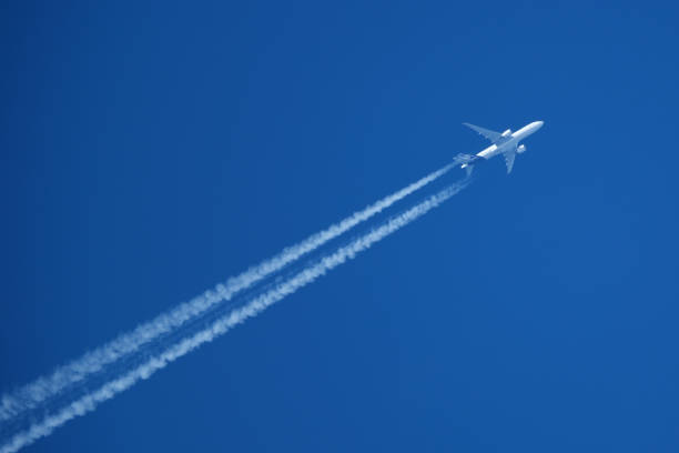 Airplane in the blue sky with contrails.