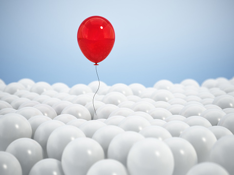 Single Red Balloon Rising Above Large Group of White Balloons Against a Blue Backdrop.