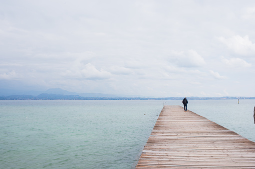 Unrecognizable man standing on pier over Garda lake, Italy