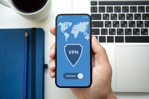 istock male hand holding phone with app vpn laptop in office 2106198780