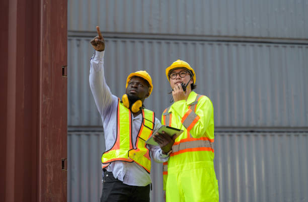 istock Asian man worker holding walkie-talkie and African engineer holding digital tablet working together at cargo shipping for containers loading 2106208007