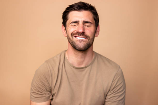 istock Man smiling with eyes closed on warm background 2106260858