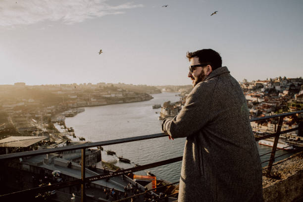 A man stands by the Douro River in Porto, admiring the scenic cityscape.