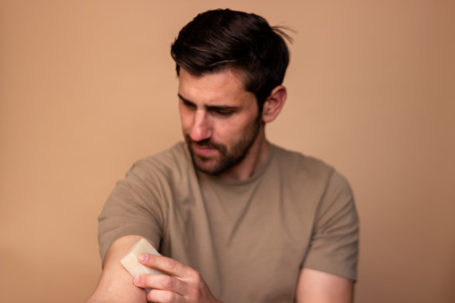 Young adult male attentively putting an adhesive bandage on his forearm