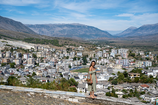 Woman walks along wall above city and mountains
